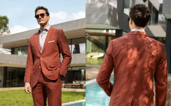 Man in a rust-colored suit, perfect semi formal attire for a wedding. He wears sunglasses and a light shirt, looking dapper outdoors.